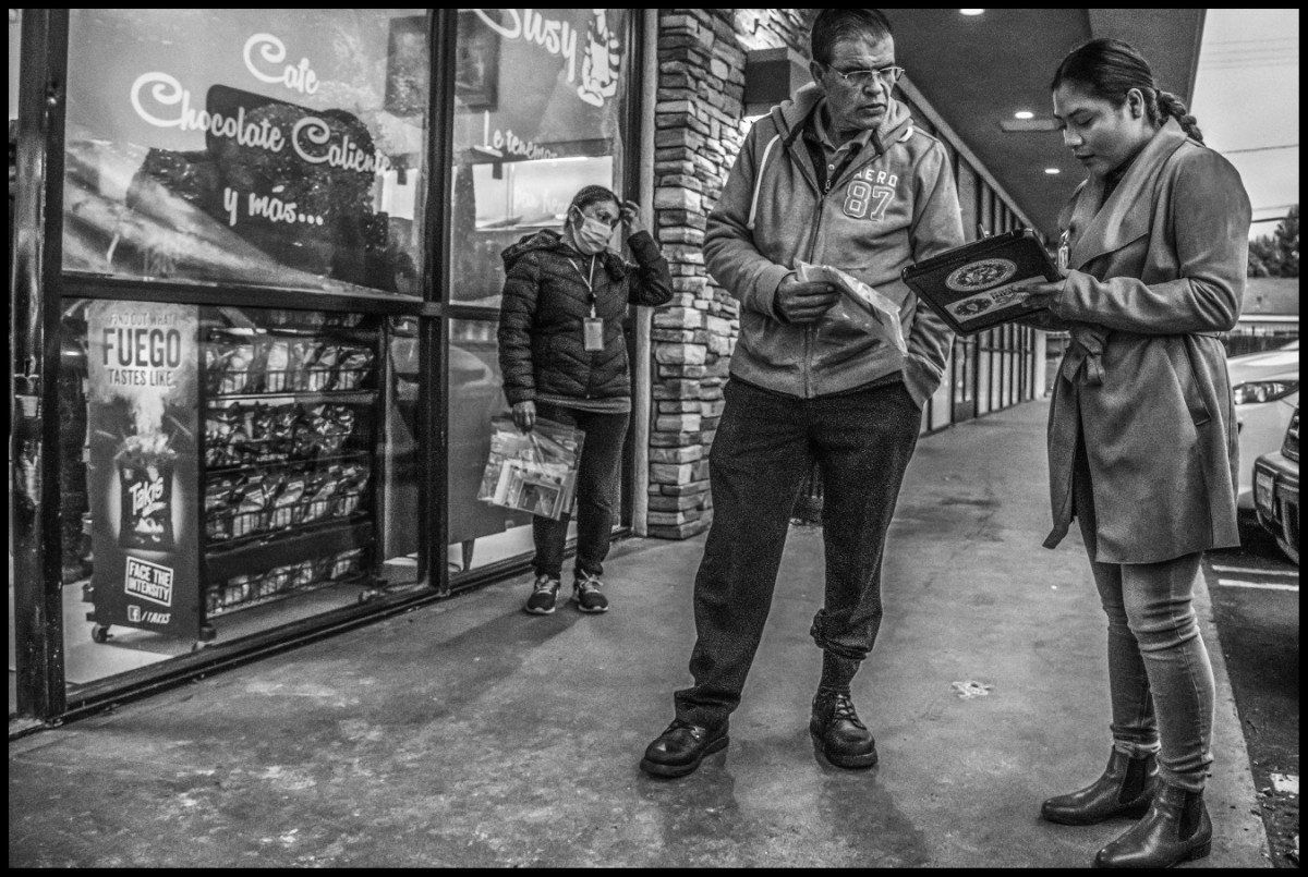Alondra Mendoza, a community outreach worker for MICOP, talks with a farmworker outside the Panaderia Susy early in the morning before work. (Photo © David Bacon)