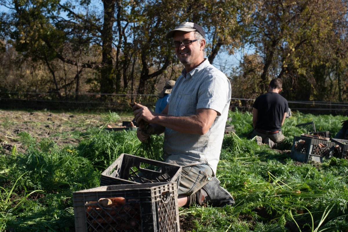 A farmer standing with a few crates in front of him