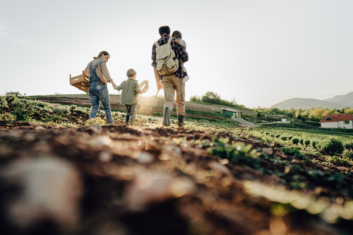a farmer family walks through a field with two kids