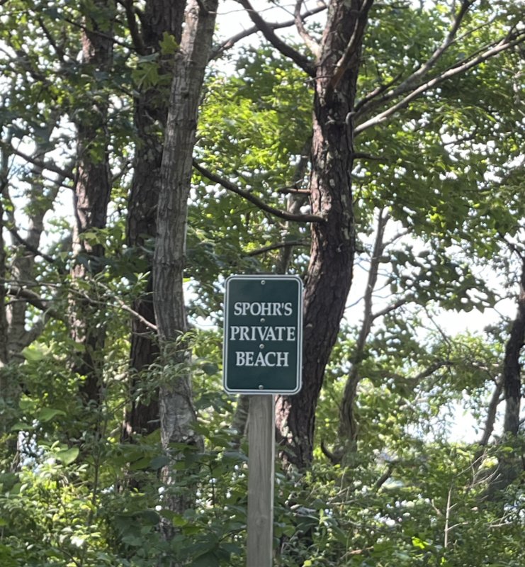 Spohr's private beach sign on a green sign in with trees in the background