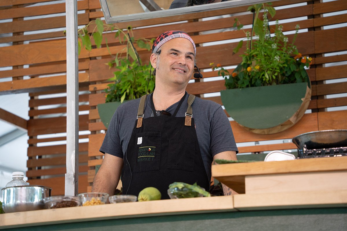 An Indigenous chef from Alaska gives a cooking demo in front of an audience