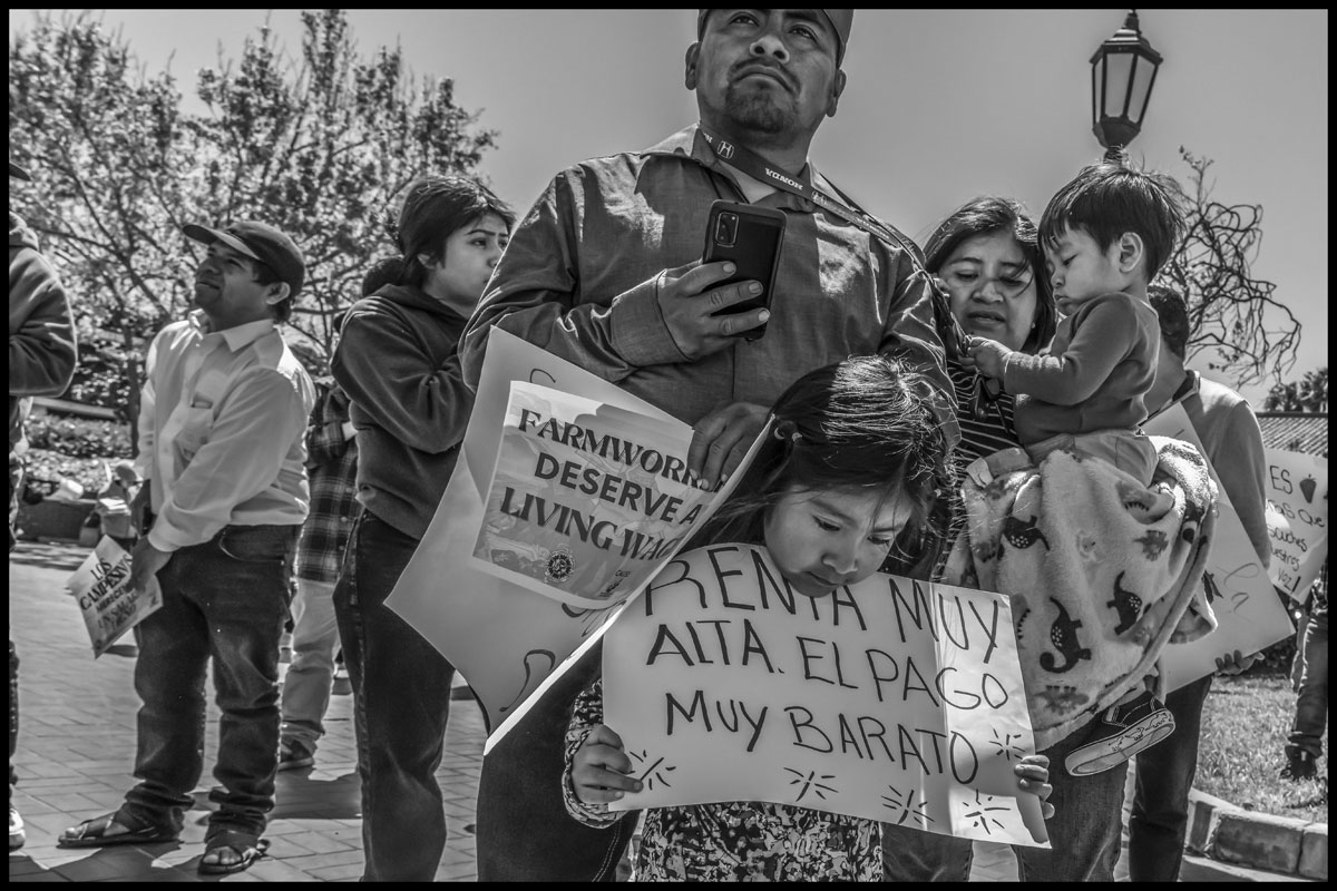 A farmworker family at a 2024 march in Santa Maria, demanding a living wage. One sign reads,