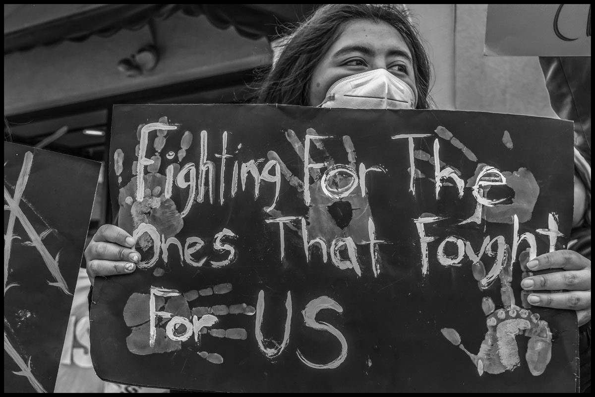 At a protest against immigration detentions in Santa Maria, CA, a young woman holds a sign honoring the work of her farmworker parents. (Photo credit: David Bacom)